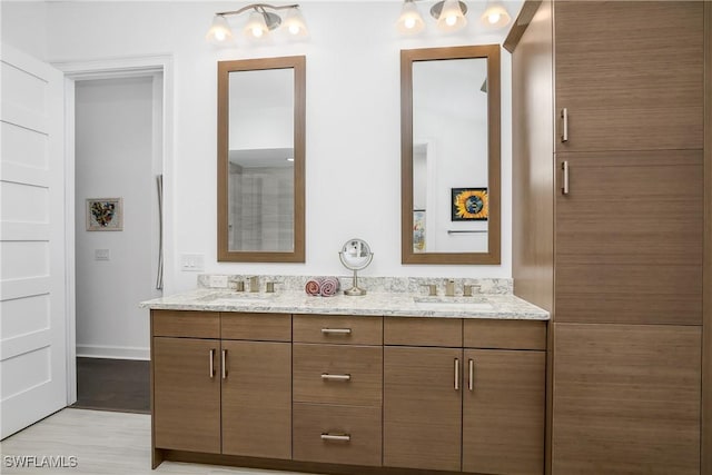 bathroom featuring double vanity, wood finished floors, baseboards, and a sink