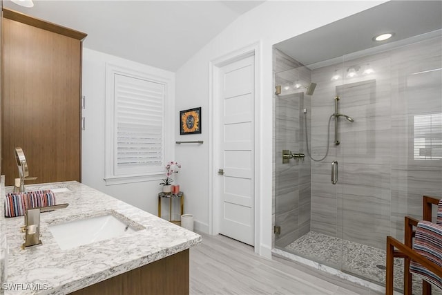 bathroom featuring a sink, double vanity, a shower stall, and vaulted ceiling