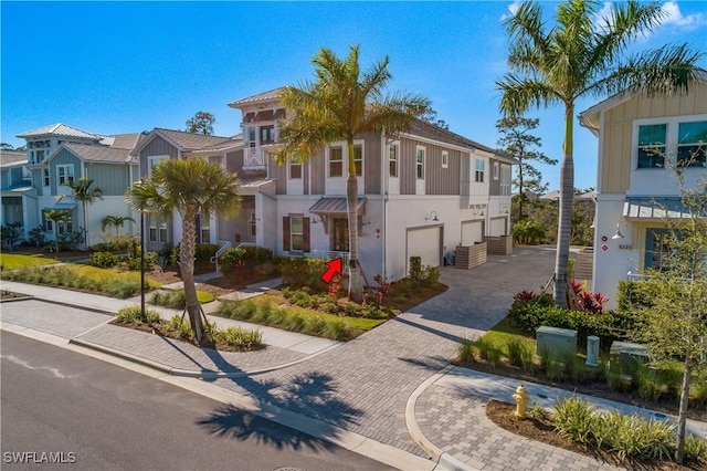 view of front of house with a residential view, stucco siding, decorative driveway, and a garage