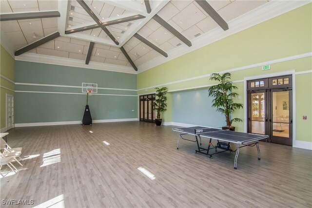 recreation room featuring french doors, baseboards, a towering ceiling, and wood finished floors