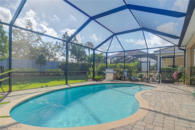 view of swimming pool with glass enclosure, a patio area, and grilling area