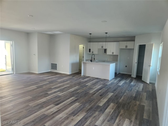 kitchen featuring dark hardwood / wood-style flooring, sink, decorative light fixtures, a center island with sink, and white cabinetry