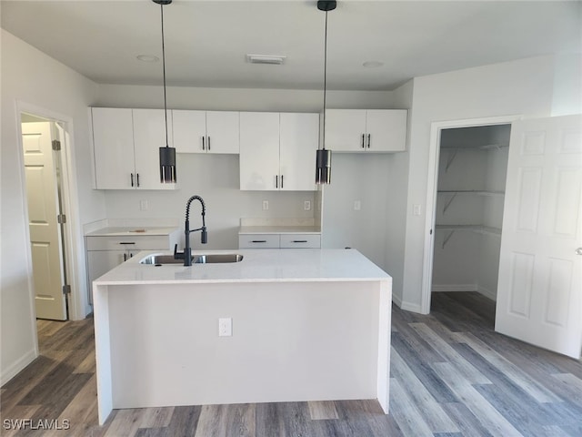 kitchen with white cabinets, decorative light fixtures, and a center island with sink