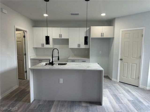 kitchen with white cabinets, pendant lighting, a center island with sink, and sink