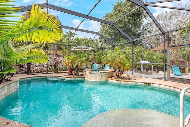 view of swimming pool featuring glass enclosure, a patio area, and an in ground hot tub