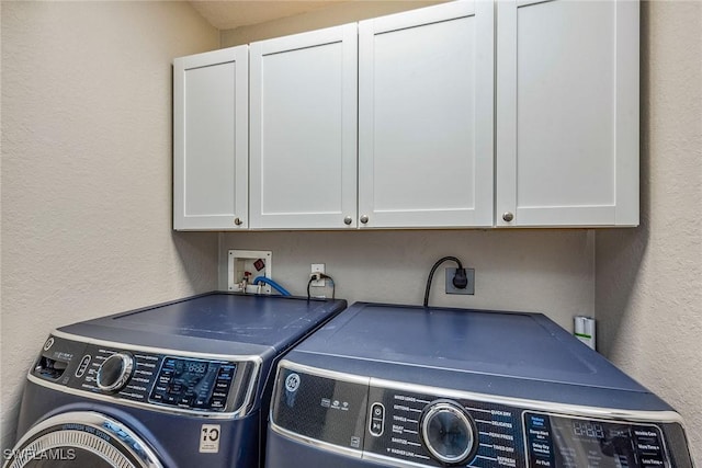 clothes washing area with washer and clothes dryer and cabinets