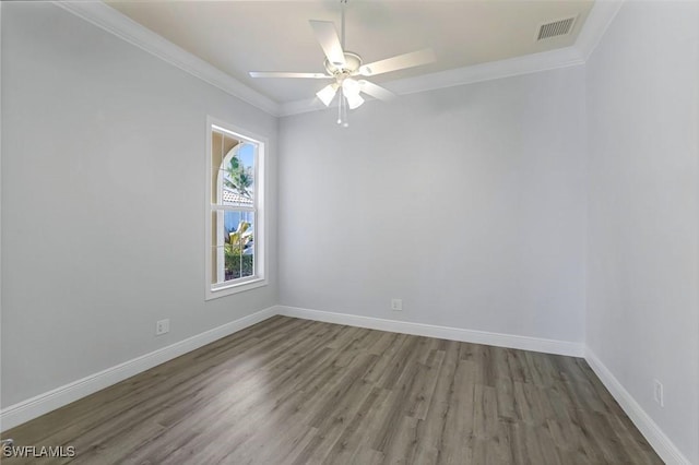 spare room featuring visible vents, wood finished floors, baseboards, and ornamental molding