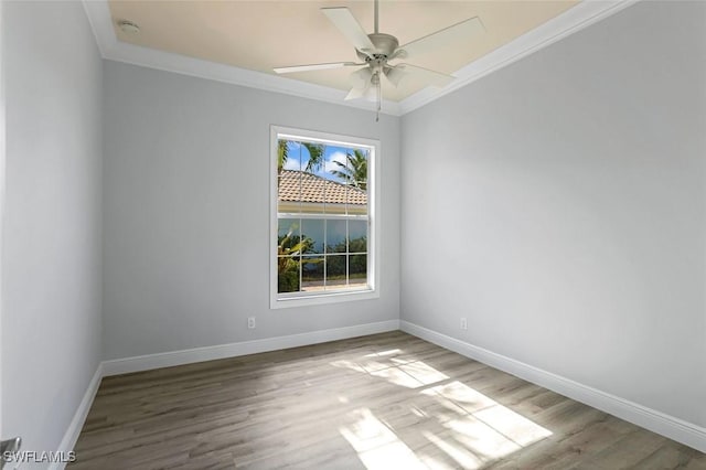 empty room with ceiling fan, baseboards, wood finished floors, and crown molding