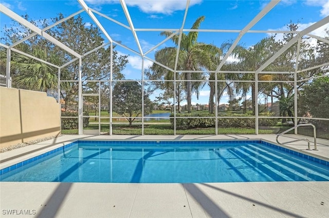 outdoor pool with a patio area, glass enclosure, and a water view