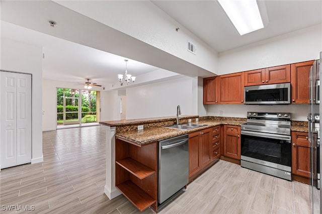 kitchen with kitchen peninsula, appliances with stainless steel finishes, ceiling fan with notable chandelier, sink, and decorative light fixtures