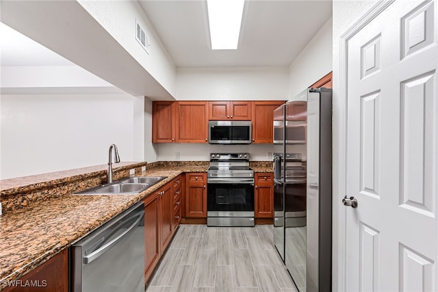 kitchen featuring dark stone countertops, sink, and appliances with stainless steel finishes