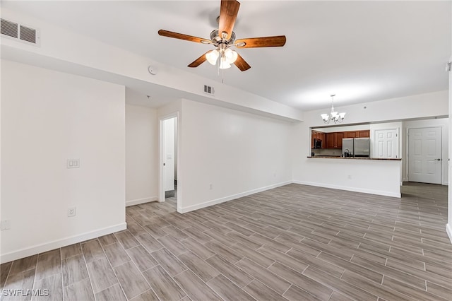 unfurnished living room with ceiling fan with notable chandelier