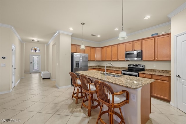 kitchen featuring sink, light stone counters, decorative light fixtures, a kitchen island with sink, and appliances with stainless steel finishes