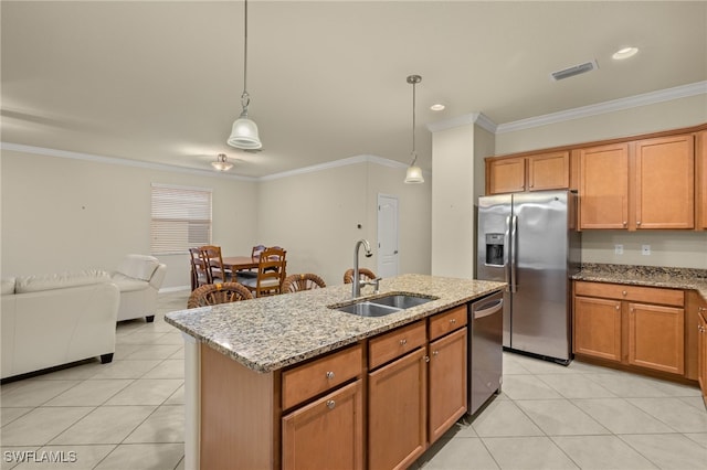 kitchen featuring a kitchen island with sink, sink, pendant lighting, and appliances with stainless steel finishes