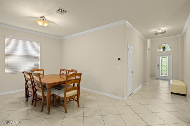 tiled dining room with a textured ceiling and crown molding