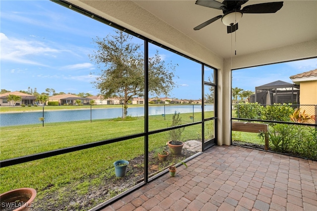 unfurnished sunroom featuring a water view and ceiling fan