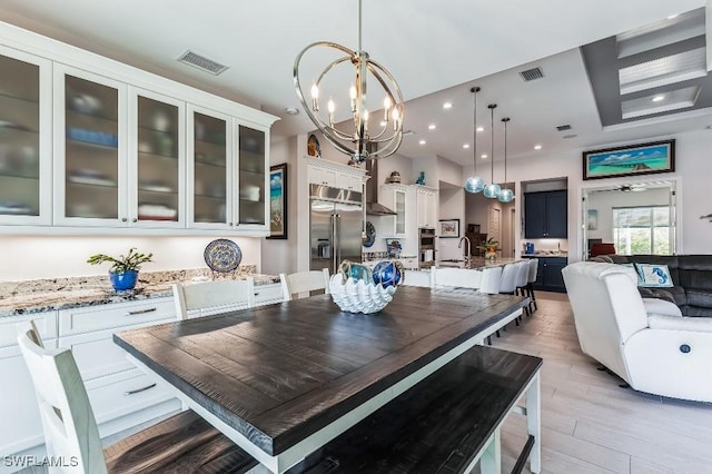 dining space featuring ceiling fan with notable chandelier and light wood-type flooring