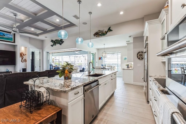 kitchen with sink, hanging light fixtures, stainless steel dishwasher, an island with sink, and white cabinets