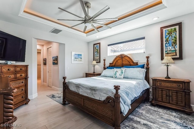 bedroom featuring a raised ceiling, ornamental molding, ceiling fan, and light hardwood / wood-style floors