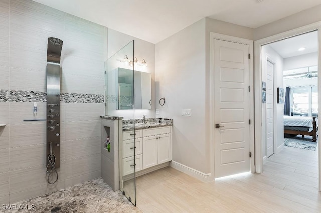 bathroom with wood-type flooring, vanity, and a tile shower