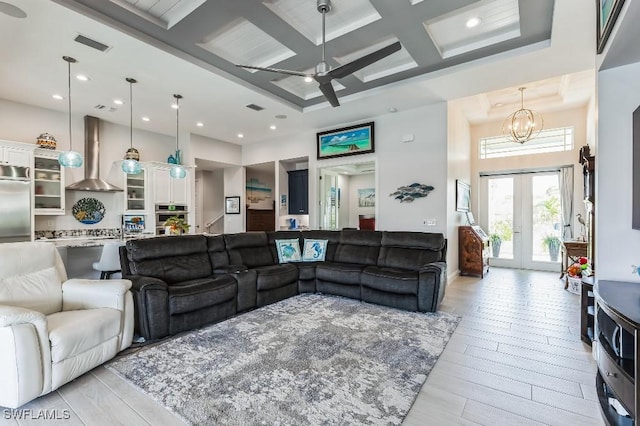 living room featuring french doors, coffered ceiling, ceiling fan with notable chandelier, and beam ceiling