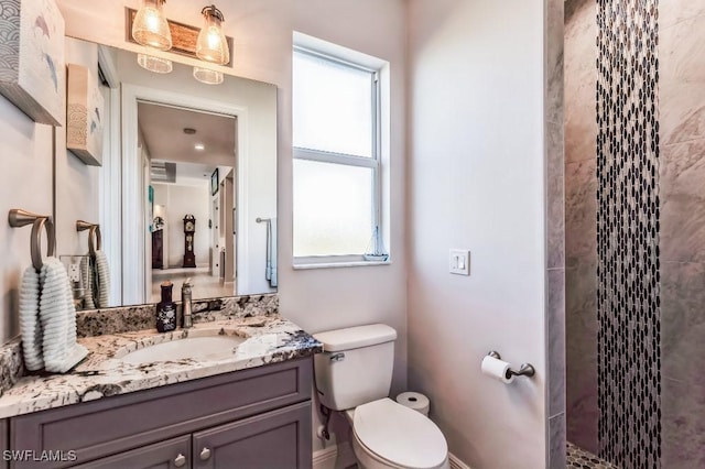 bathroom with vanity, toilet, and a tile shower