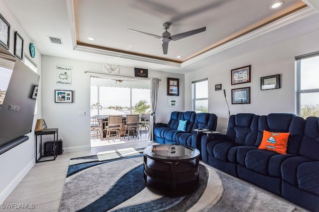 living room featuring a healthy amount of sunlight, a tray ceiling, crown molding, and ceiling fan