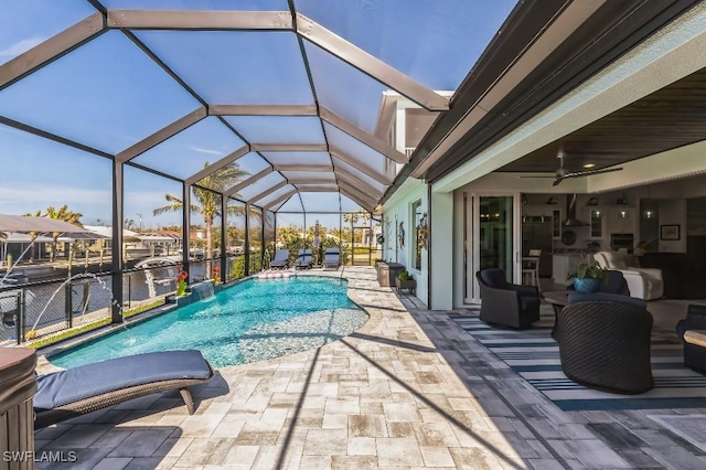 view of pool with pool water feature, a water view, glass enclosure, ceiling fan, and a patio