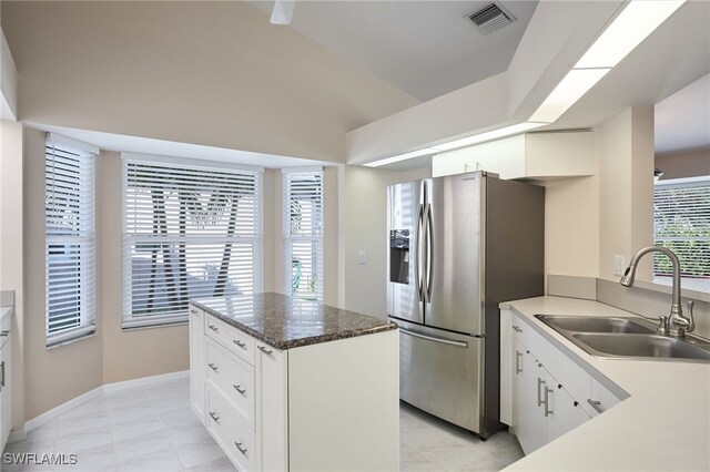 kitchen with stainless steel fridge, white cabinetry, and sink