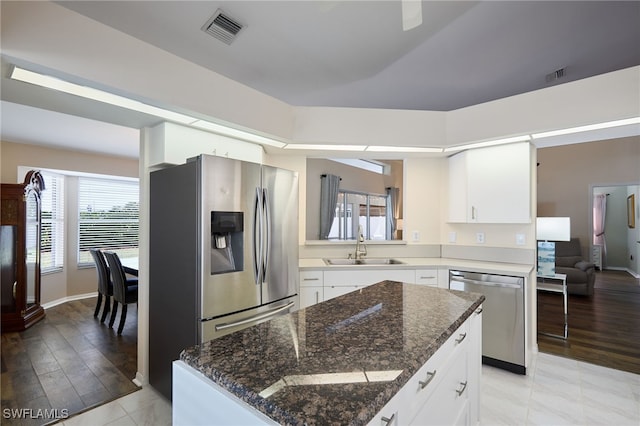 kitchen with white cabinets, stainless steel appliances, dark stone countertops, and sink