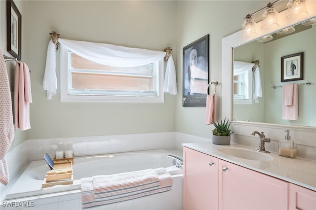 bathroom with tiled tub, plenty of natural light, and vanity