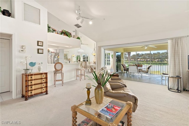 living room with ceiling fan, carpet floors, and high vaulted ceiling