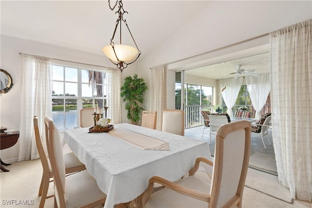 dining space featuring ceiling fan, a water view, light carpet, and lofted ceiling