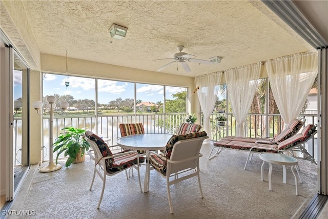 unfurnished sunroom featuring ceiling fan with notable chandelier and a water view