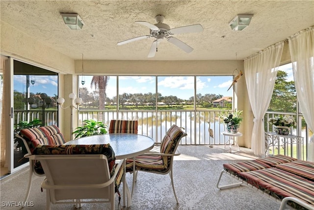 sunroom / solarium with ceiling fan and a water view