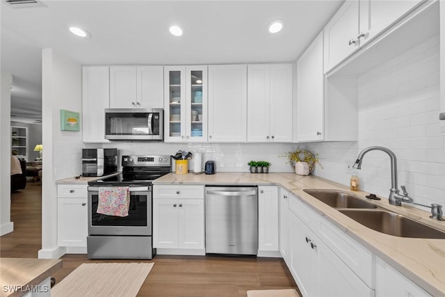 kitchen featuring sink, tasteful backsplash, light stone counters, white cabinetry, and stainless steel appliances