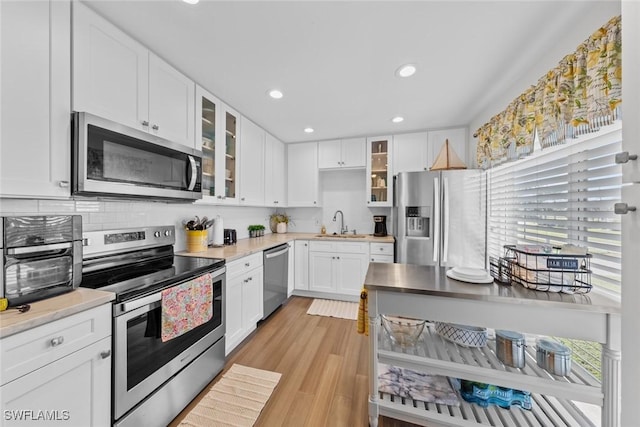 kitchen with light wood-type flooring, white cabinetry, sink, and appliances with stainless steel finishes