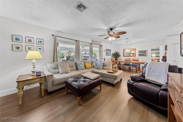 living room with wood-type flooring, a textured ceiling, and ceiling fan