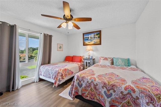 bedroom with ceiling fan, wood-type flooring, and a textured ceiling