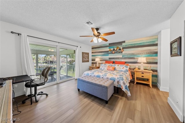 bedroom featuring a textured ceiling, access to outside, light hardwood / wood-style flooring, and ceiling fan