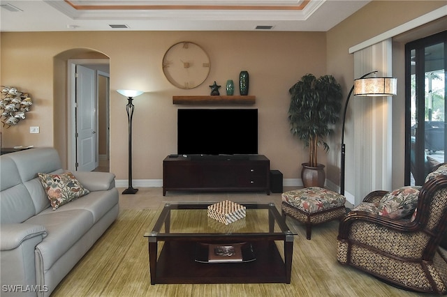 living area with arched walkways, a raised ceiling, and visible vents