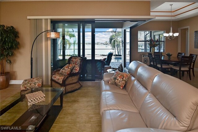 living room with baseboards, an inviting chandelier, and a water view