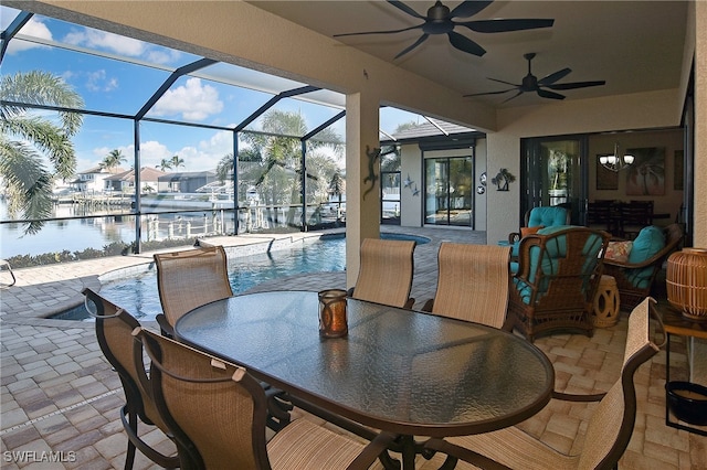 view of patio / terrace featuring glass enclosure, ceiling fan, and a water view