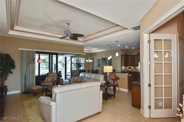 living room with ceiling fan, french doors, light tile patterned floors, a tray ceiling, and ornamental molding