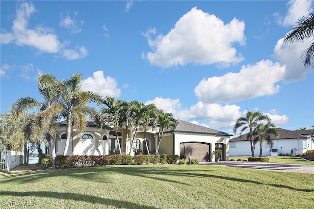 view of front of home featuring an attached garage, driveway, a front yard, and stucco siding