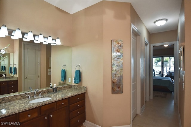ensuite bathroom featuring vanity, tile patterned floors, baseboards, and connected bathroom