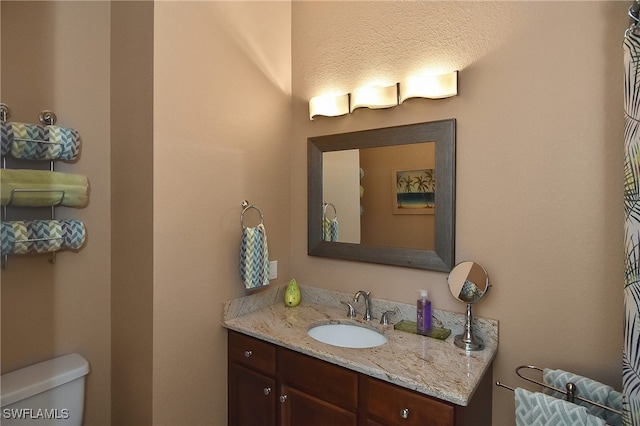 bathroom featuring toilet, a textured ceiling, and vanity