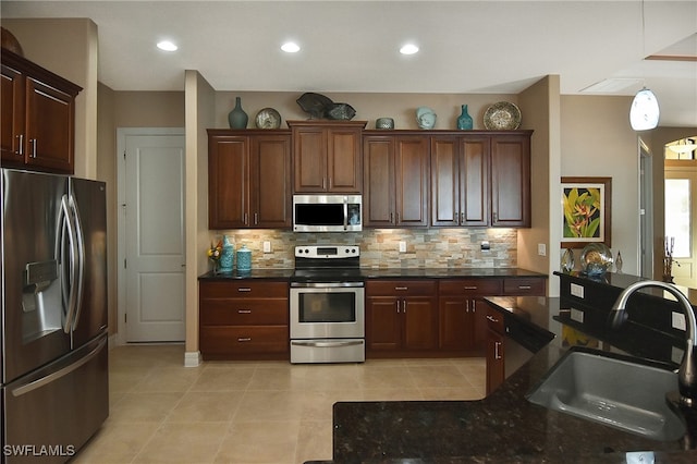 kitchen with stainless steel appliances, dark stone countertops, decorative backsplash, sink, and light tile patterned flooring