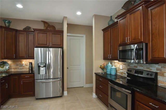 kitchen featuring dark stone countertops, light tile patterned floors, stainless steel appliances, and tasteful backsplash