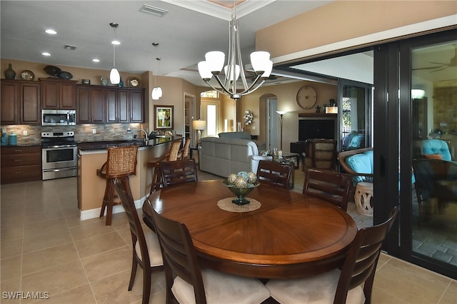 tiled dining area featuring crown molding and an inviting chandelier